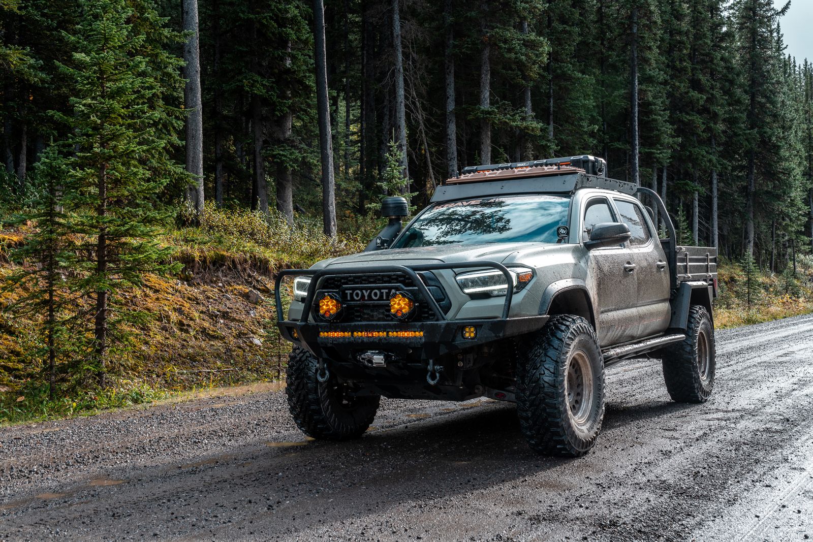 Toyota Tacoma truck on a forest road with off-road equipment.